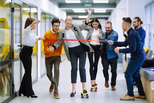 Group of coworkers having fun with skateboard in the office