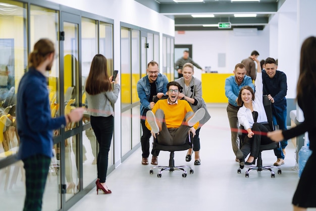 Group of coworkers having fun with skateboard in the office