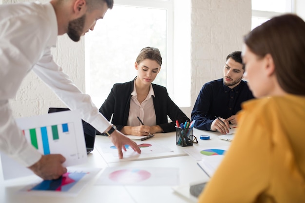 Group of creative people working together on new project Young girl in shirt and jacket thoughtfully working while spending time in modern office