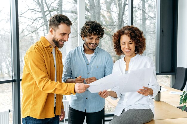 A group of creative successful people colleagues at work looking through documents in a modern office analyzing financial statements satisfied with the results smiling discussing prospects