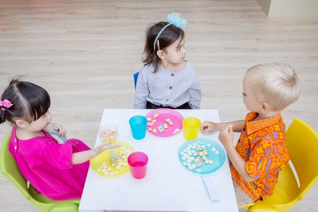 Group of cute kids eating breakfast in kindergarten