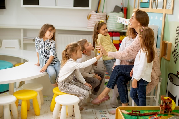 Foto un gruppo di simpatici bambini in età prescolare ha messo le mani insieme alla loro maestra d'asilo