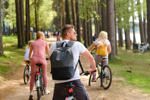A group of cyclists with backpacks ride bicycles on a forest road enjoying nature