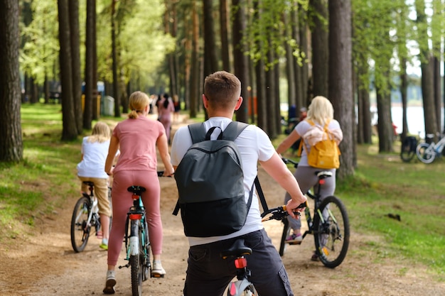 A group of cyclists with backpacks ride bicycles on a forest road enjoying nature.