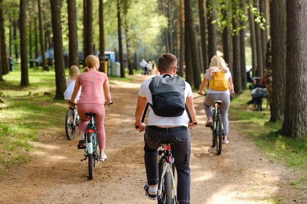 A group of cyclists with backpacks ride bicycles on a forest road enjoying nature.