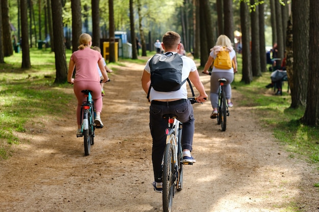 A group of cyclists with backpacks ride bicycles on a forest road enjoying nature.