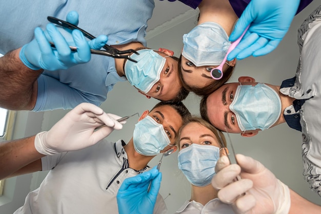 Group of dentists holding medical instruments and stant in a circle at a meeting Patient hospital