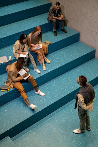 Photo group of diligent students making notes in copybooks