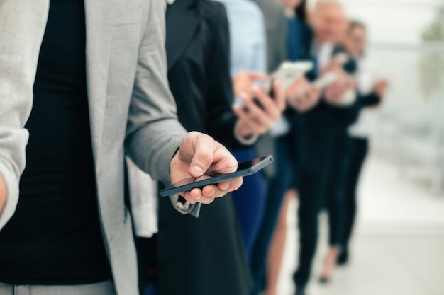 Group of diverse employees with smartphones standing in a row
