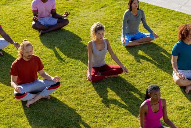 Group of diverse friends doing yoga and meditating in garden. Friendship, healthy and active lifestyle, summer, sunshine, unaltered.