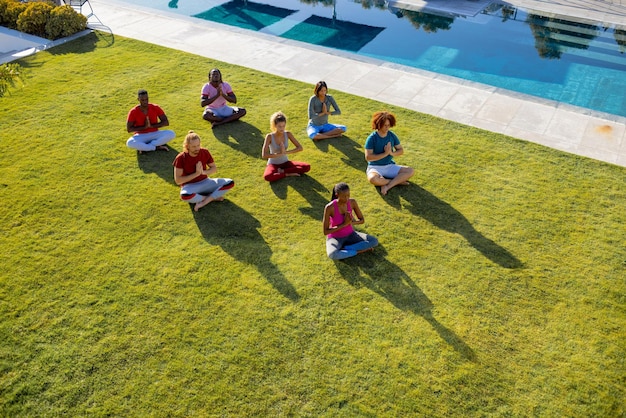 Group of diverse friends doing yoga and meditating in garden. Friendship, healthy and active lifestyle, summer, sunshine, unaltered.