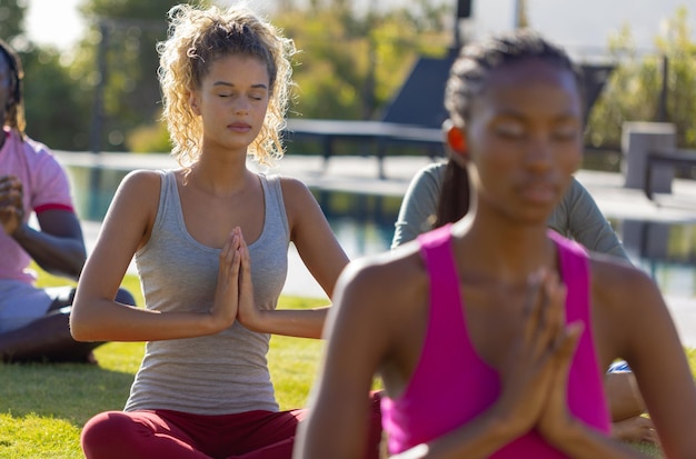 Group of diverse friends doing yoga and meditating in garden