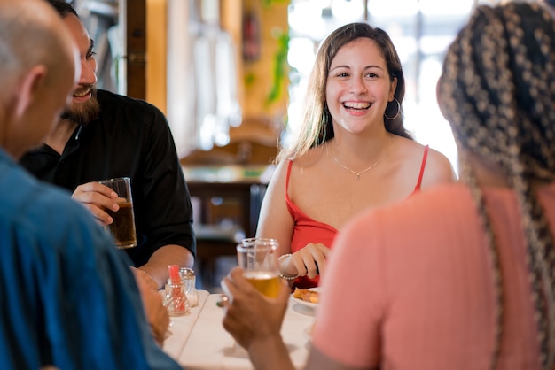 Group of diverse friends drinking beer while enjoying a meal together in a restaurant. Friends concept.