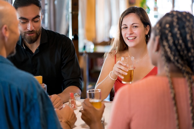 group of diverse friends drinking beer while enjoying a meal together in a restaurant. friends concept.