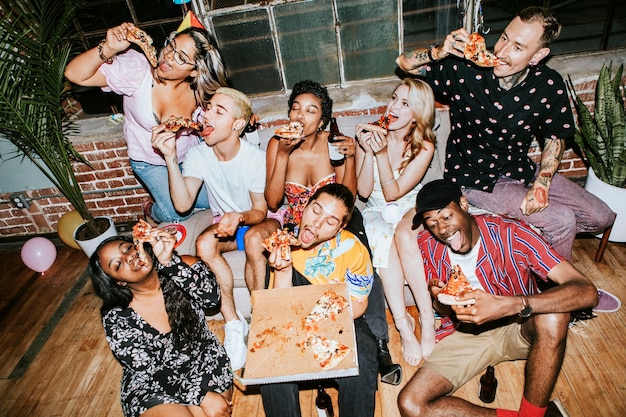 A group of diverse friends enjoying pizza  at a party