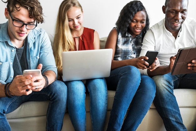 Foto gruppo di amici diversi appendere fuori e utilizzando dispositivi digitali