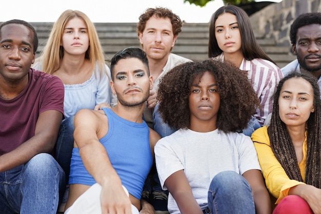 Group of diverse friends sitting in the city and looking serious on camera - Multiracial people and diversity concept