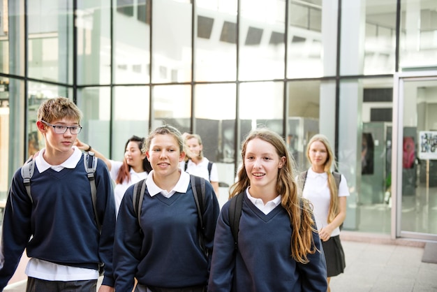 Group of diverse happy students in school uniform walk together after school class Diverse group of students smile and walk in school uniforms Diverse happy group of student friends walk together