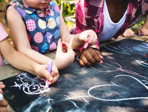 Photo group of diverse kids drawing on chalkboard together