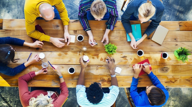 A group of diverse people are sitting around a wooden table having a meeting