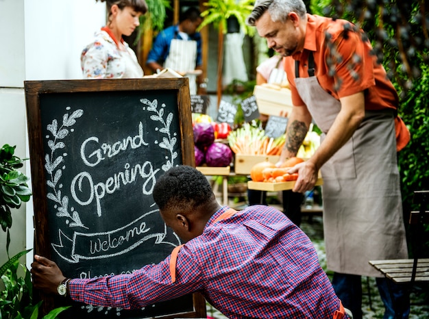 Group of diverse people with store grand opening board