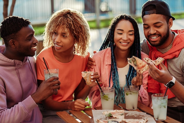 Group of diverse positive African American friends meeting at birthday party in cafe drinking