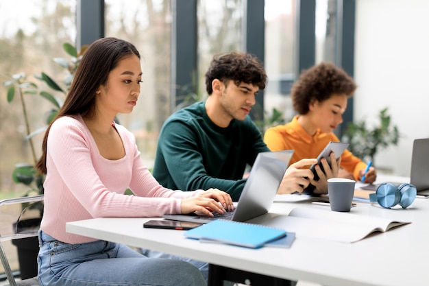 Group of diverse students studying for test making project or homework together focus on asian lady