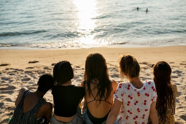 Группа различных женщин, сидевших на пляже вместе