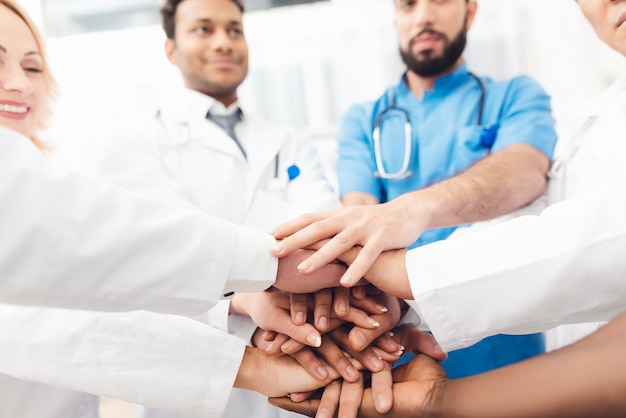 A group of doctors are holding each other's hands.