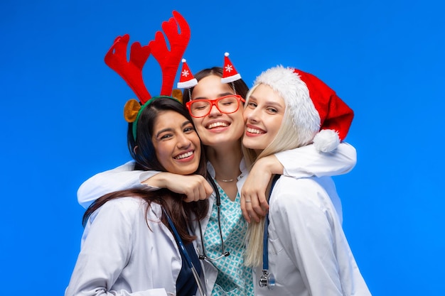 A group of doctors celebrates winter holidays in the studio. Three beautiful girls doctors of different nations wish Merry Christmas. Happy New Year!