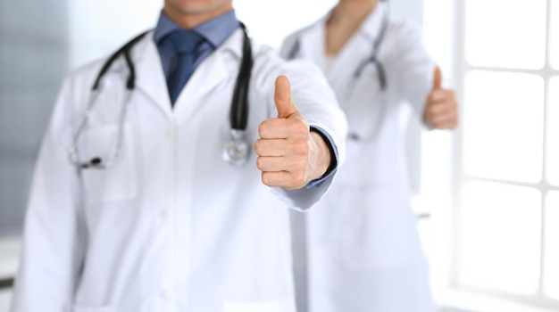 Group of doctors cheerful smiling at camera, thumbs up. Perfect medical service in clinic. Happy future in medicine and healthcare.