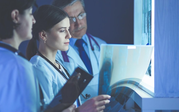 Photo group of doctors examining xrays in a clinic thinking of a diagnosis