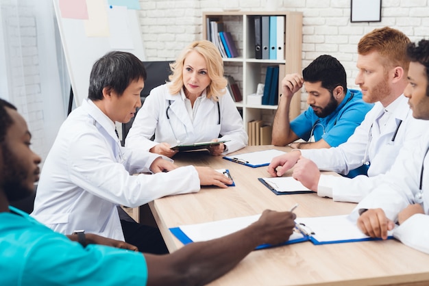 Group of doctors from different races is meeting at a table.