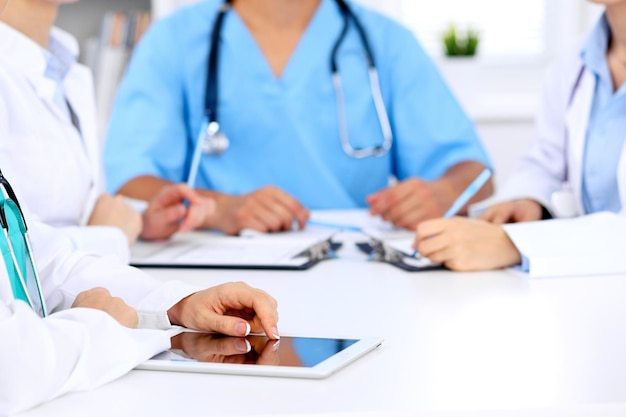 Group of doctors at medical meeting. Close up of physician using tablet computer.