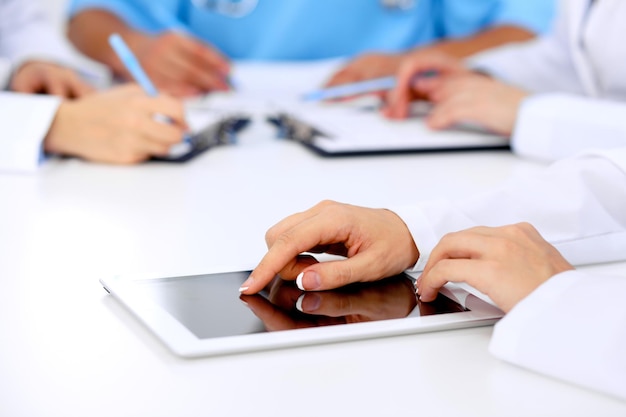 Group of doctors at medical meeting. Close up of physician using tablet computer.