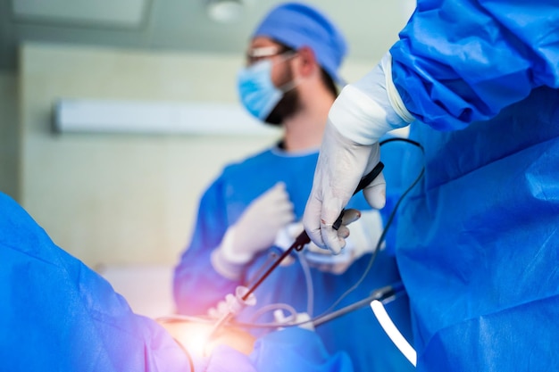 Group of doctors perform an operation to a patient surgeons in medical uniform and masks working in the operating room