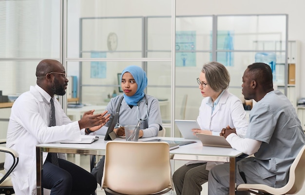 Group of doctors sitting at table and planning work together during meeting in office