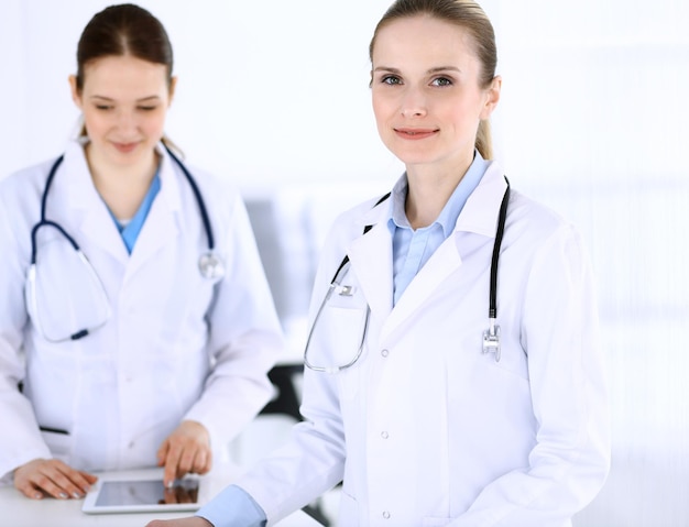 Group of doctors at work in hospital physician filling up\
medical documents or prescription while standing at reception desk\
data in medicine and health care concept