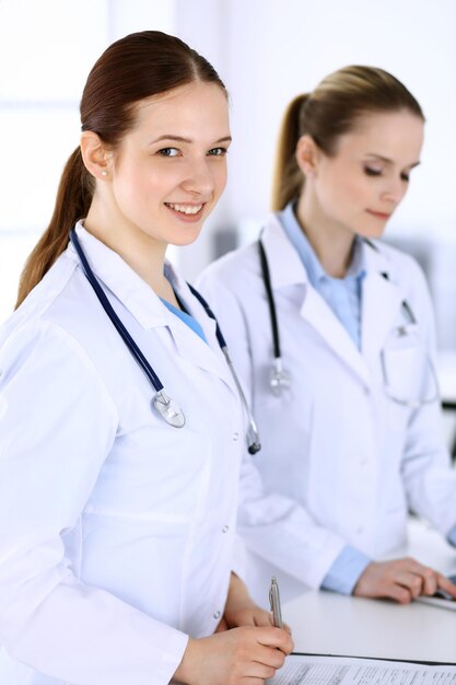 Group of doctors at work in hospital Physician filling up medical documents or prescription while standing at reception desk Data in medicine and health care concept