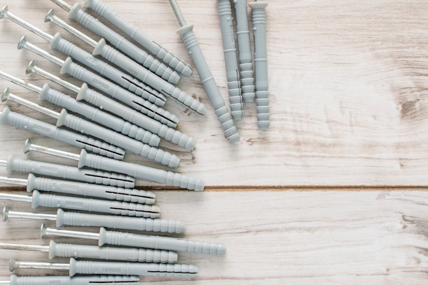 Photo group of dowels and nails on wooden background. dowels for fastening in concrete. flat lay top view with a copyspace for text. stock photo