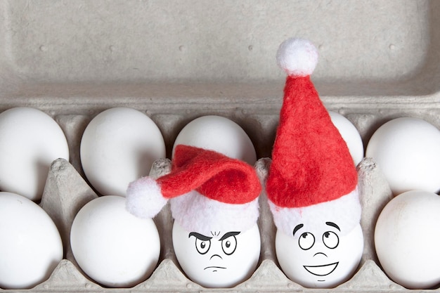 Group of eggs in toy christmas hats with drawn emotions