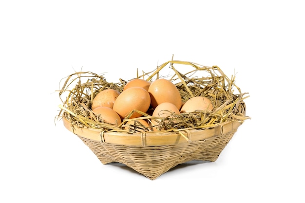 Группа яиц с соломой в бамбуковой корзине, изолированные на белом