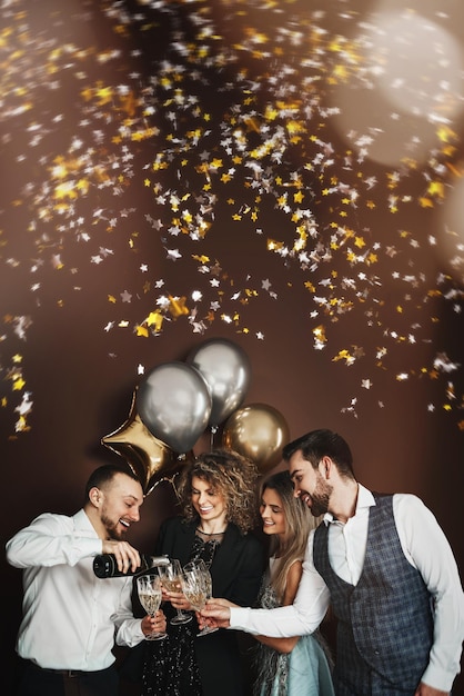 Foto gruppo di persone elegantemente vestite che celebrano una vacanza o un evento bevendo spumante