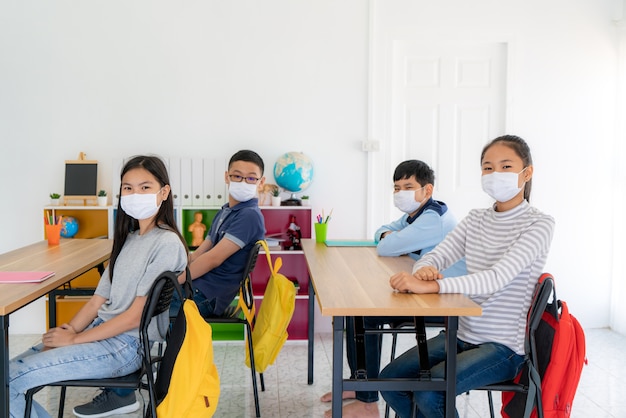 Group of elementary school students wearing hygienic mask in classroom and smiling to be happy while back to school reopen their school, New normal for education concept.