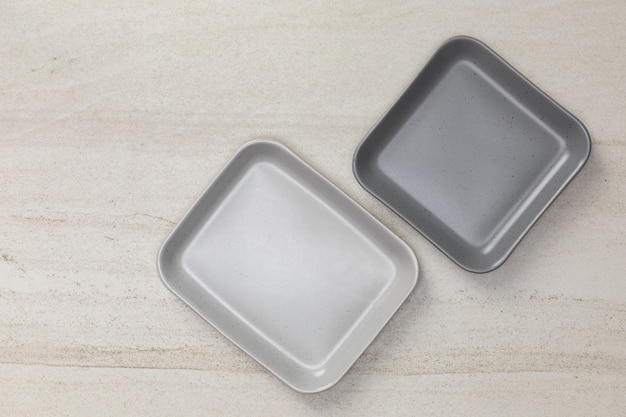 Group of empty blank ceramic square plates on white stone blackground, top view of traditional handcrafted kitchenware concept