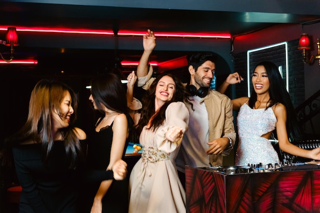 Group of energetic women dancing friends with DJ enjoying night party Young women dance in the night