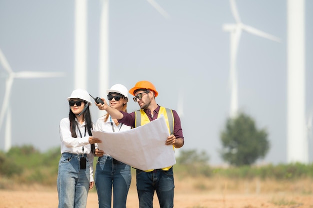 Group of engineers and architects on construction site with wind turbines in background