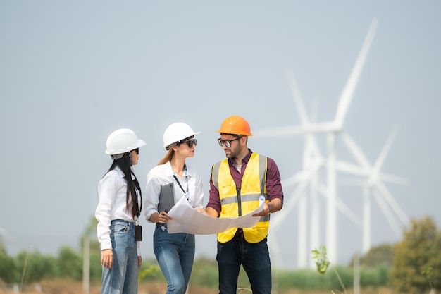 Group of engineers and architects on construction site with wind turbines in background