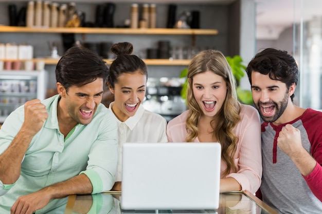 Group of excited friends using laptop