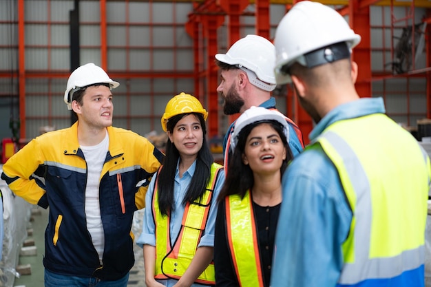 Group of factory workers in hardhats with joint hands together for celebrating success